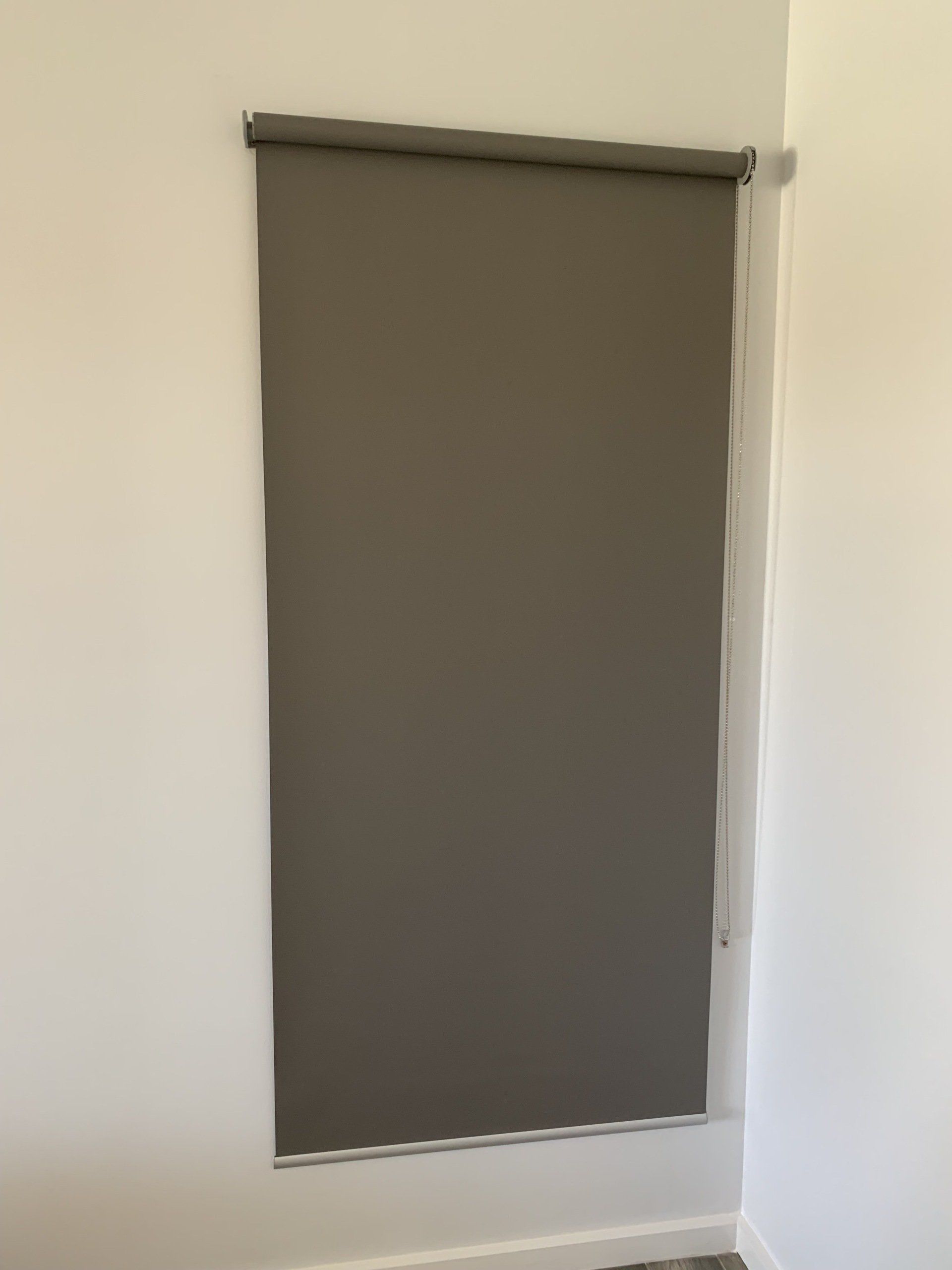 Grey Roller Blind Installed in A Corner Against a White Wall — Alice Mobile Blinds in Ciccone, NT