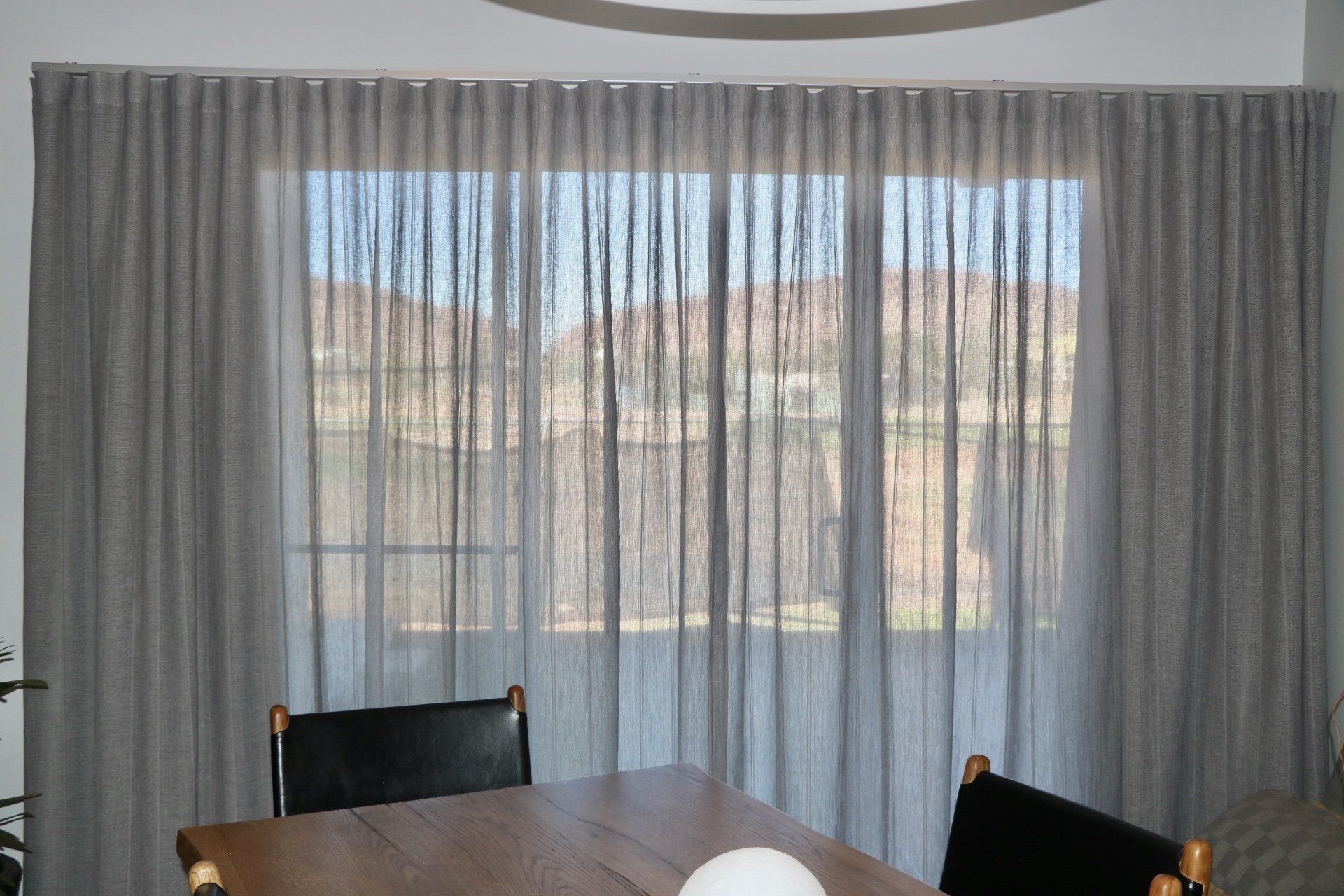 Grey Curtains Frame a Window Filtering Light — Alice Mobile Blinds in Ciccone, NT