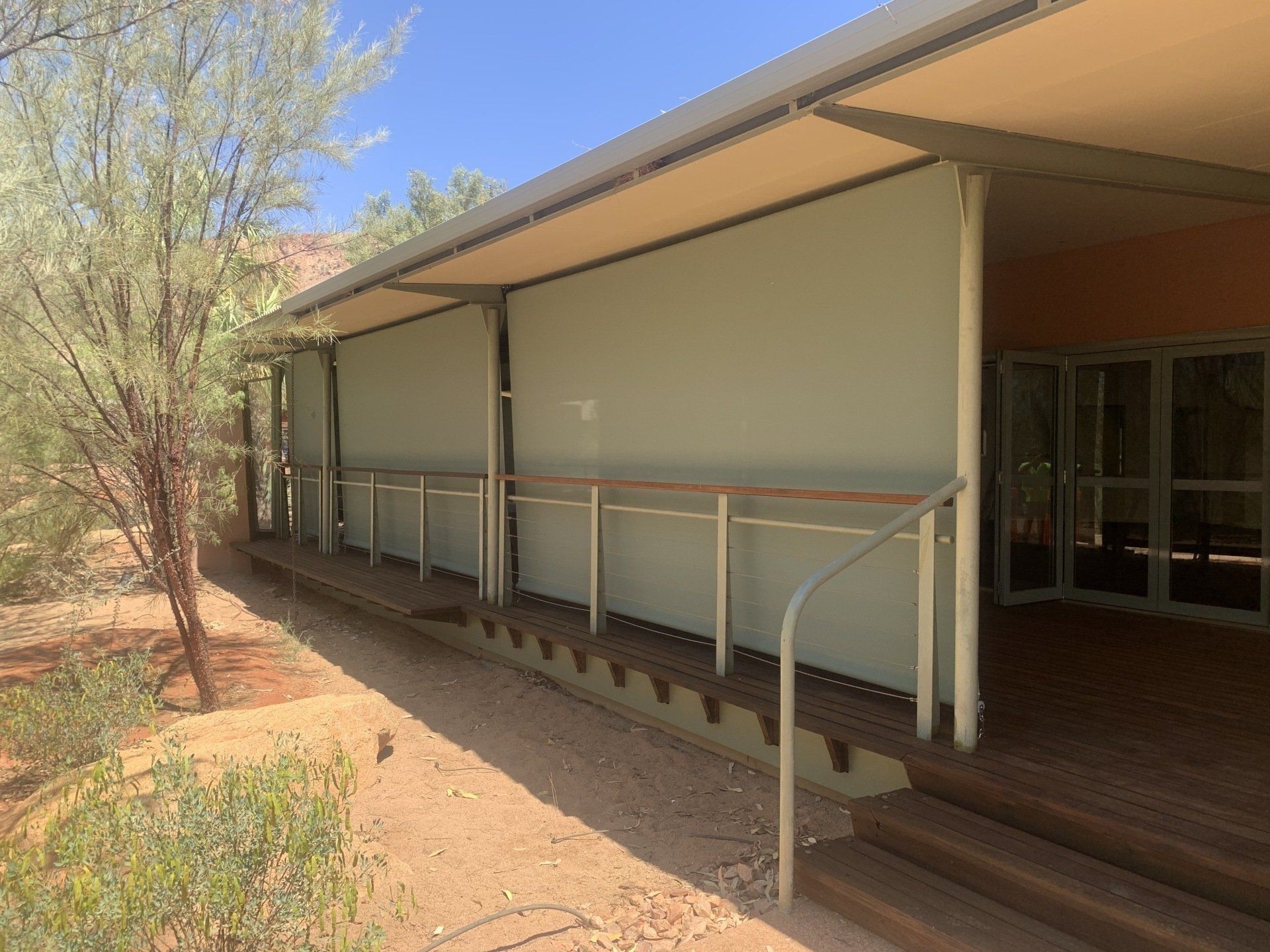 Building with A Shaded Porch, Awnings, Wooden Deck and Railing — Alice Mobile Blinds in Ciccone, NT