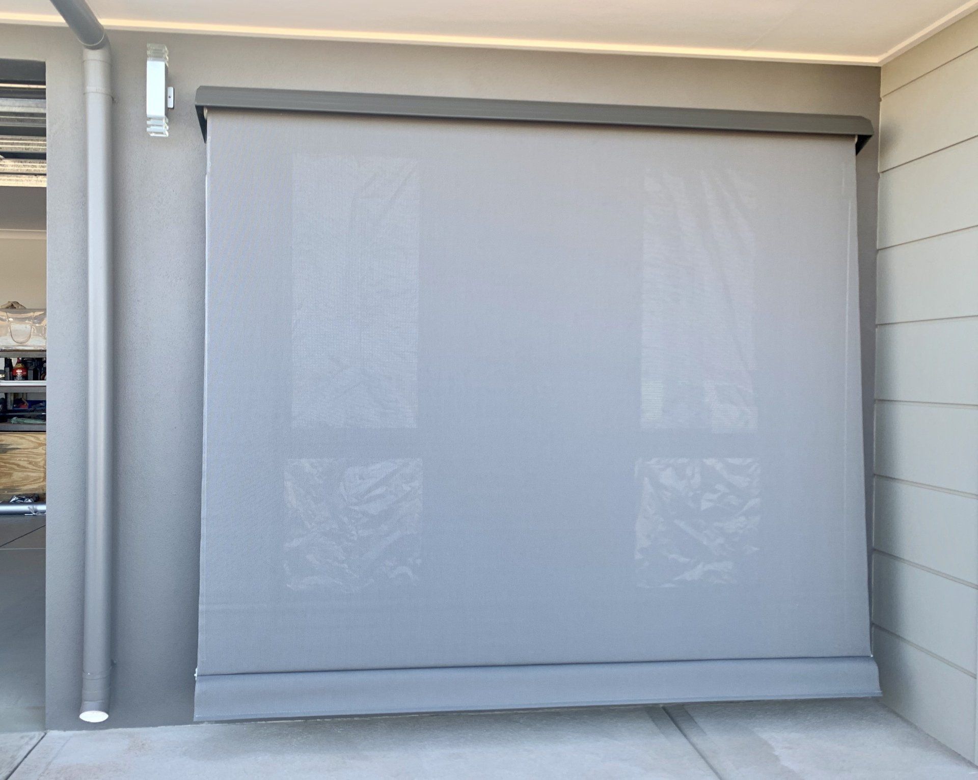 Grey Outdoor Roller Shade Partially Lowered Against a Wall — Alice Mobile Blinds in Ciccone, NT