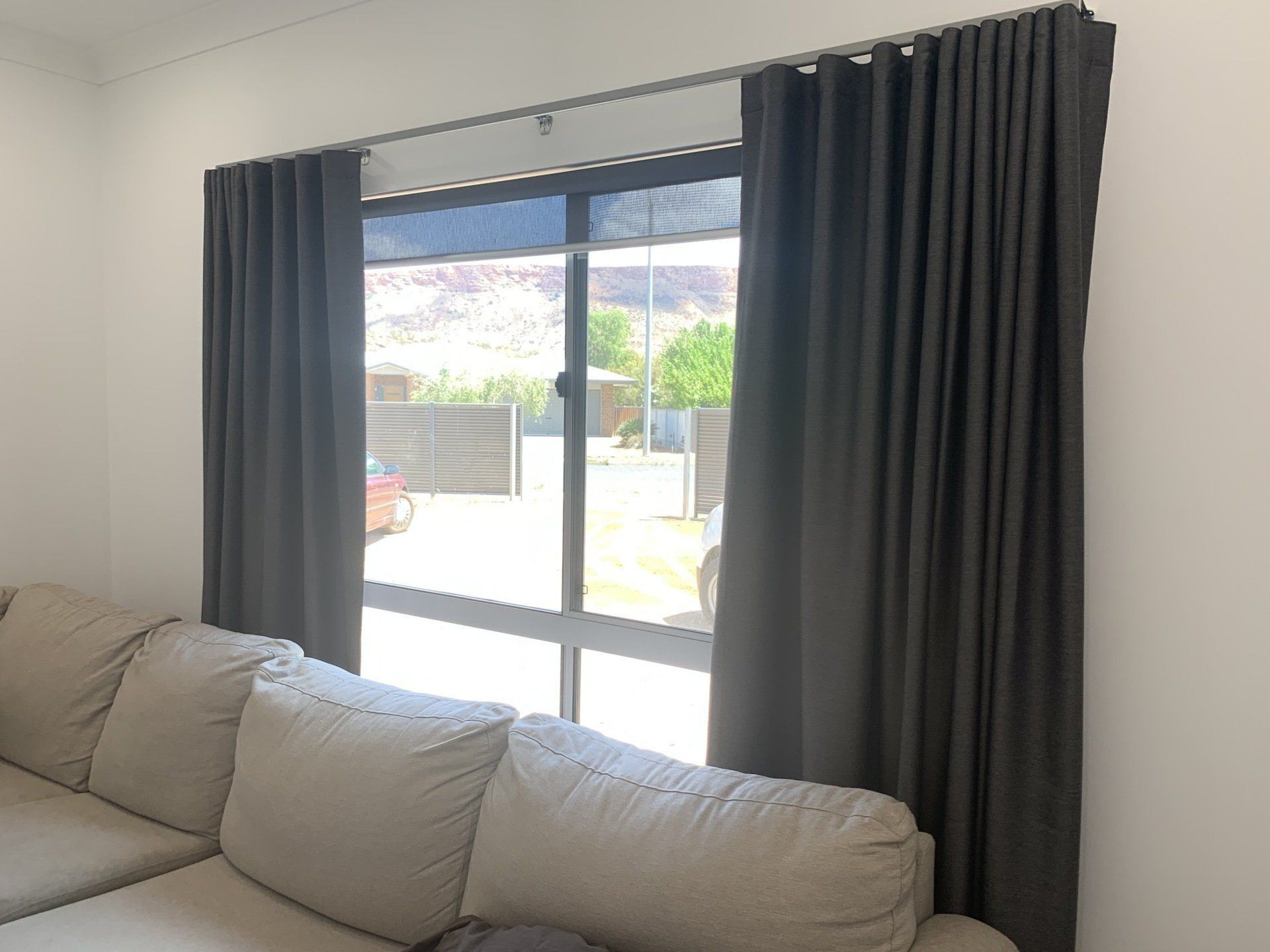 Grey Curtains Framing a Window Behind a Beige Couch — Alice Mobile Blinds in Ciccone, NT