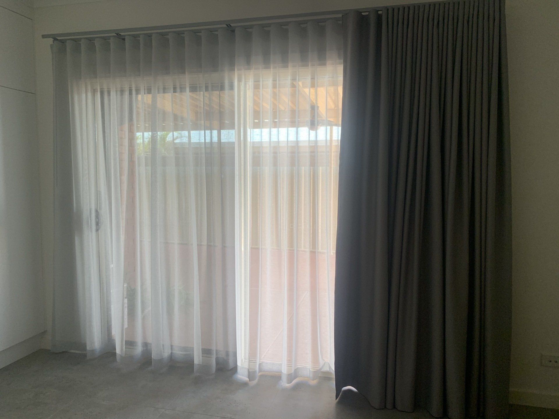 Grey and White Curtains Hang in Front of A Window — Alice Mobile Blinds in Ciccone, NT