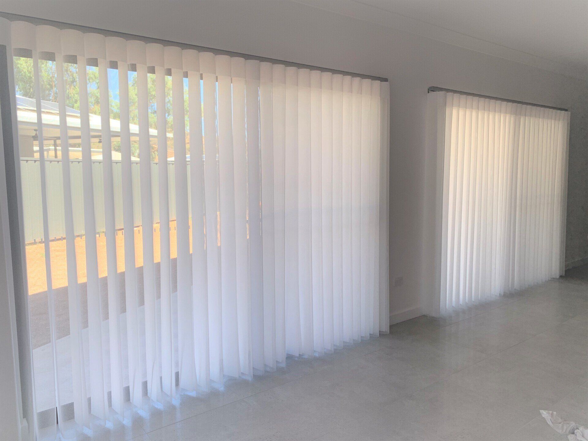 Two Windows with White Vertical Blinds in A Bright Room — Alice Mobile Blinds in Ciccone, NT