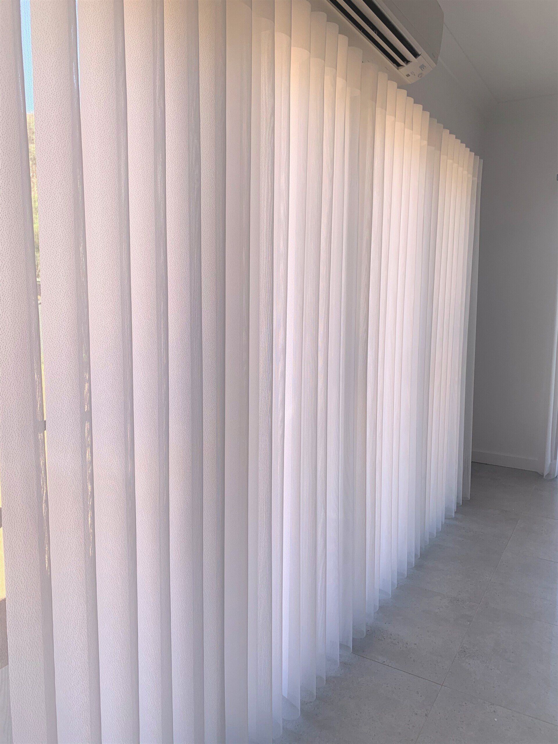 White Vertical Blinds Partially Covering a Wall with A Doorway Visible — Alice Mobile Blinds in Ciccone, NT