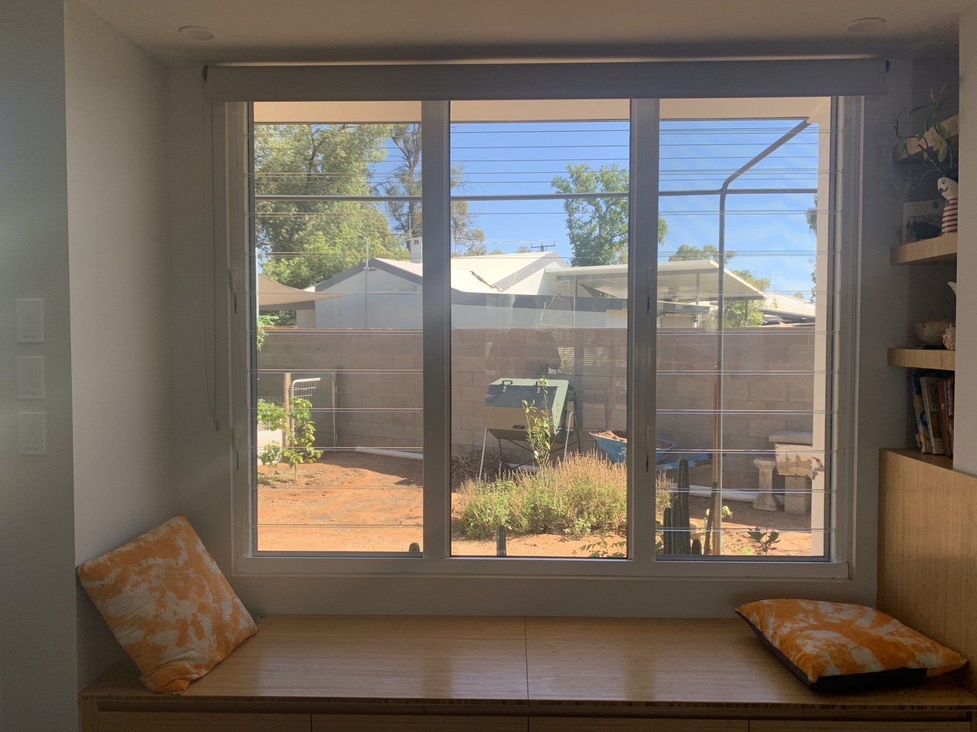 Window Seat with Orange Pillows Looking out At a Backyard — Alice Mobile Blinds in Ciccone, NT