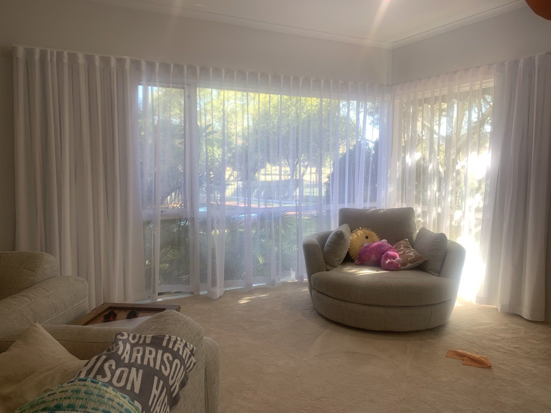 Living Room with White Curtains, a Round Chair and A Beige Sofa — Alice Mobile Blinds in Ciccone, NT