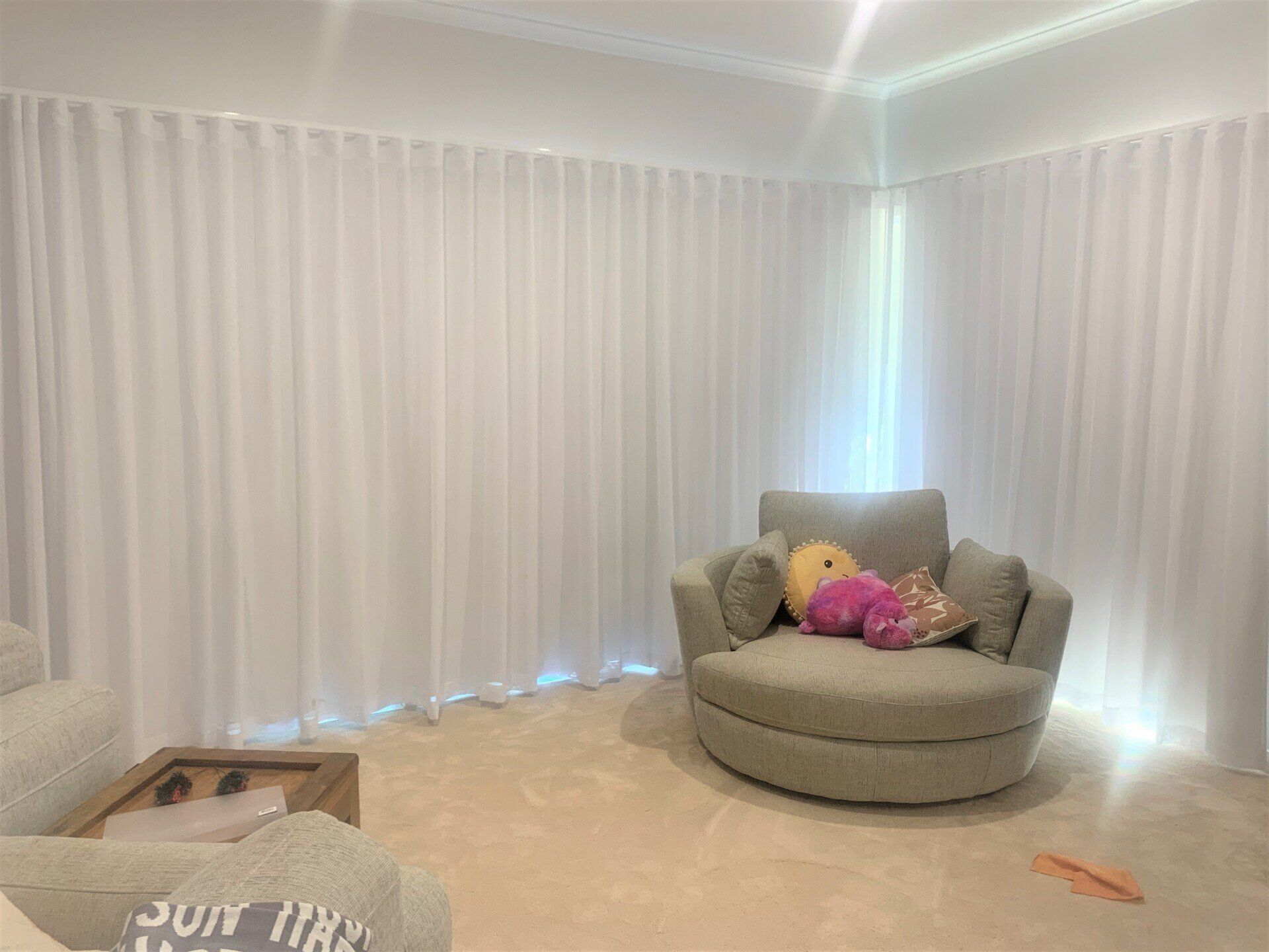 White Curtains Frame a Room with A Round Grey Armchair — Alice Mobile Blinds in Ciccone, NT