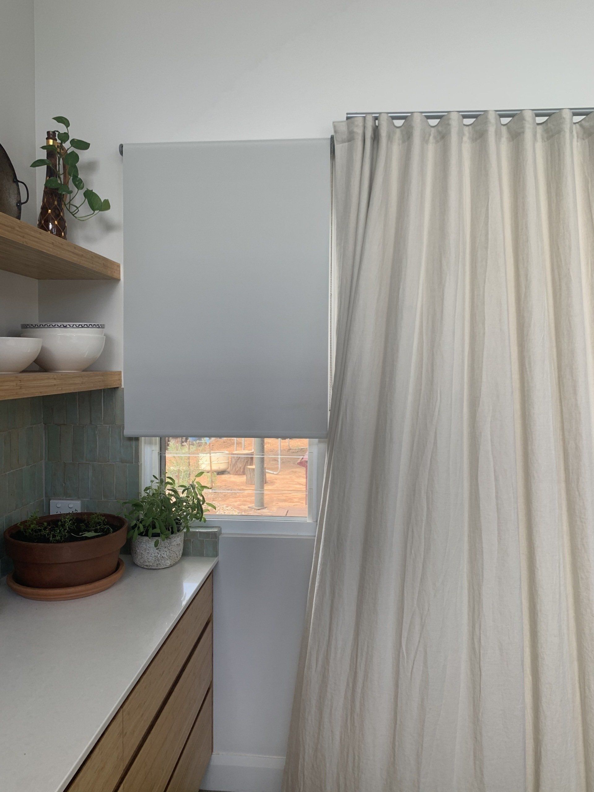 A Kitchen Window with A Roller Shade and Sheer Curtains — Alice Mobile Blinds in Ciccone, NT