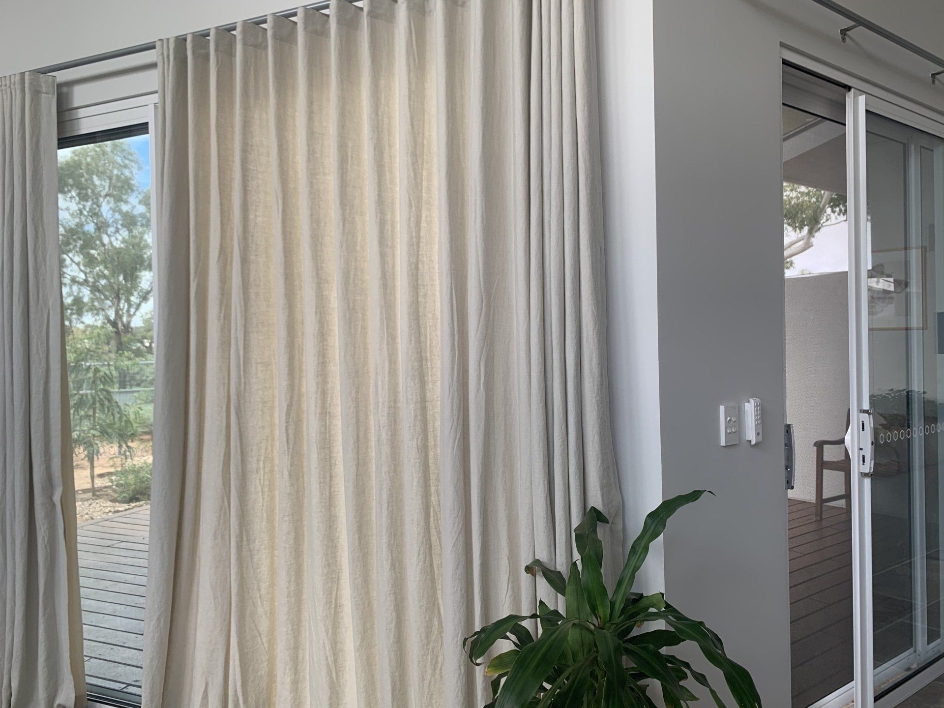 Beige Curtains Hang in Front of A Glass Door — Alice Mobile Blinds in Ciccone, NT