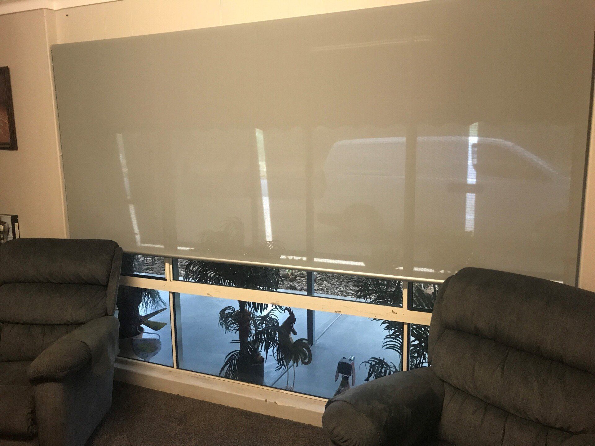 Two Grey Recliners Face a Large Window with Beige Roller Blinds — Alice Mobile Blinds in Ciccone, NT