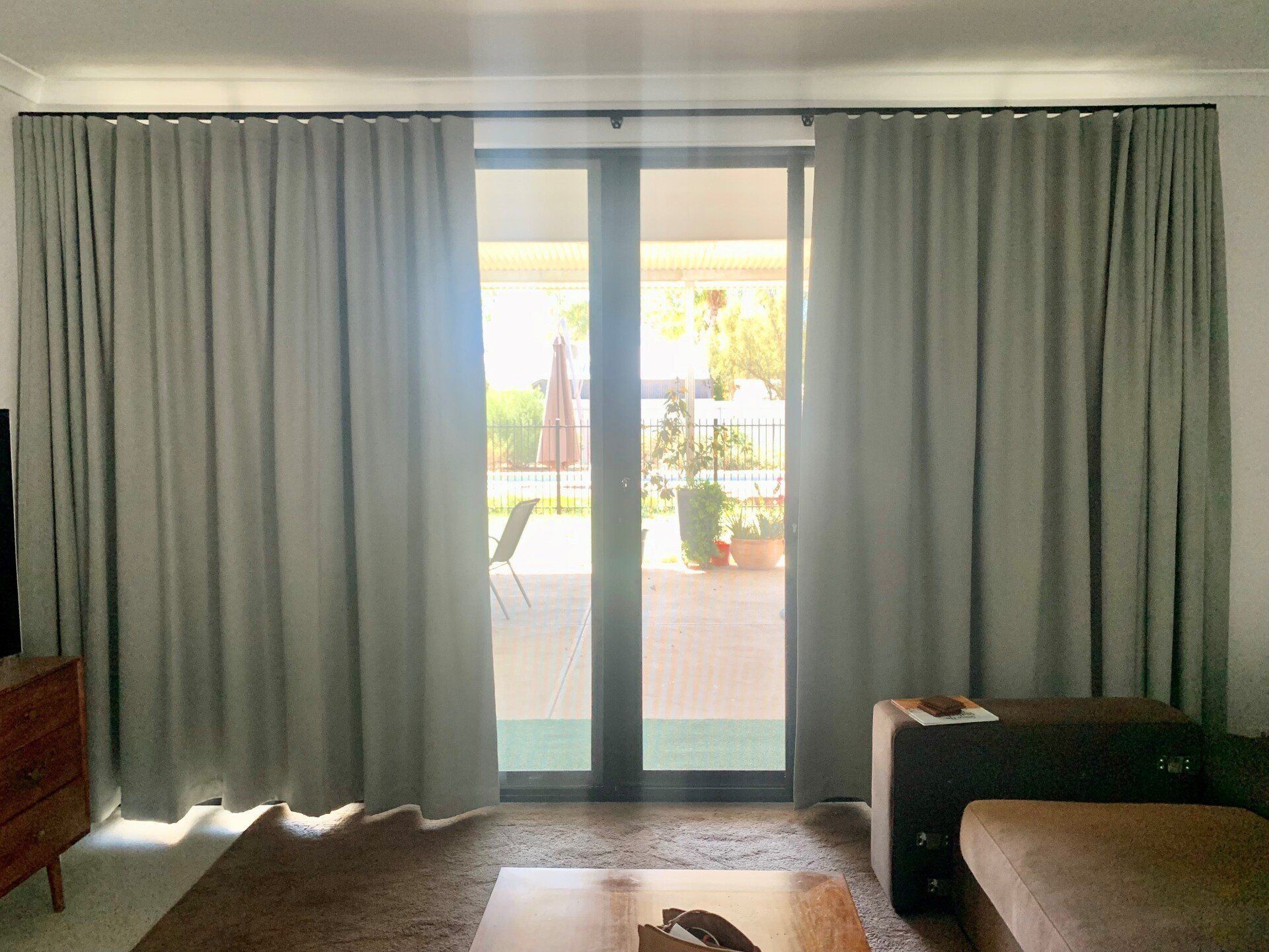 Grey Curtains Framing a Glass Door Opening onto A Patio — Alice Mobile Blinds in Ciccone, NT
