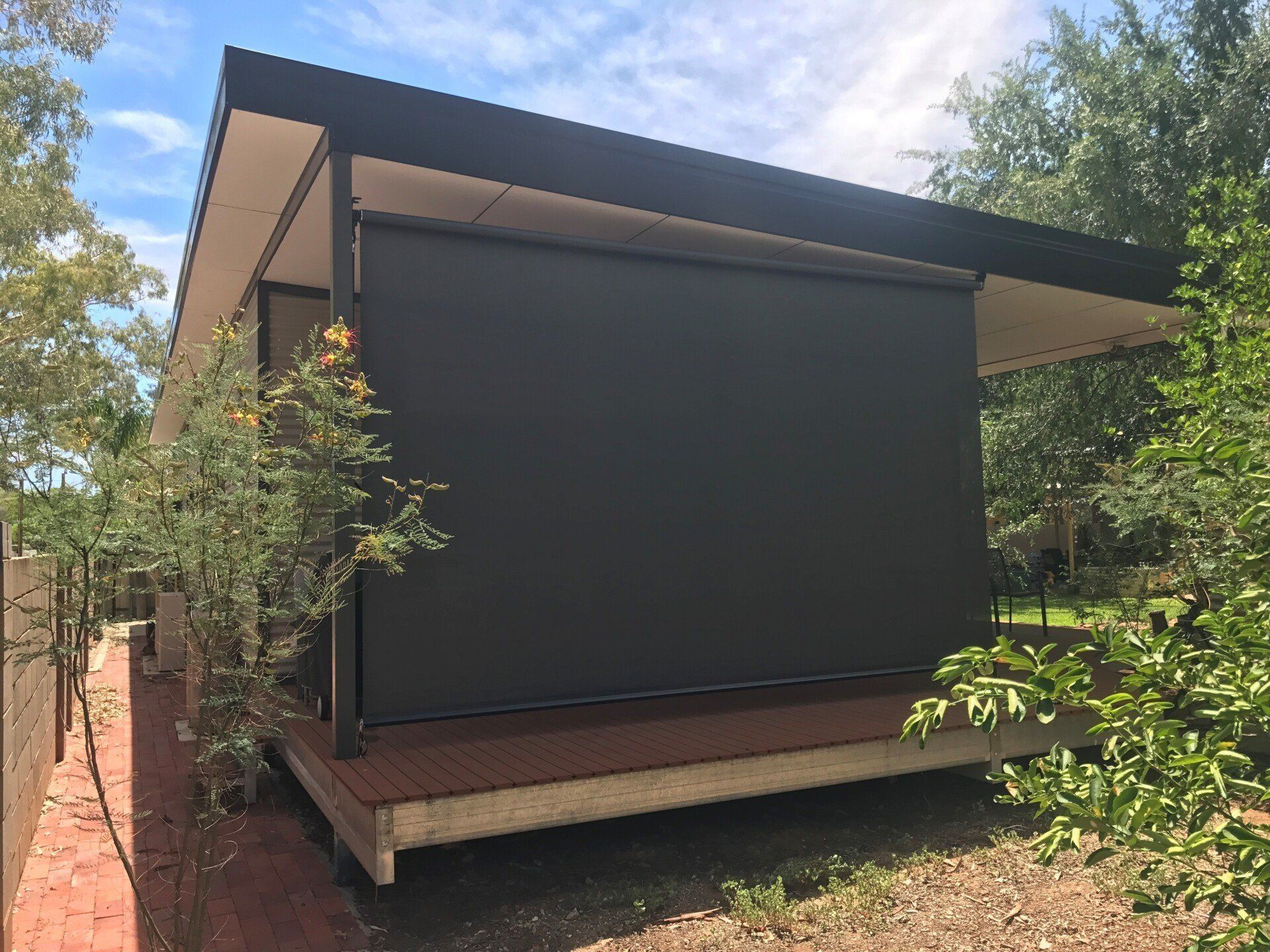 Black Exterior Shade on A Wooden Deck of A Modern Building — Alice Mobile Blinds in Ciccone, NT