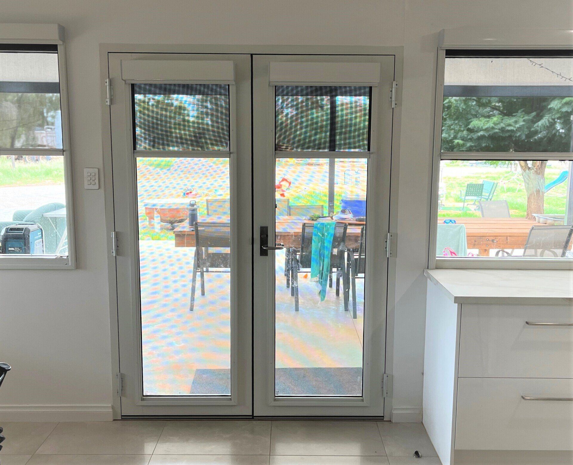 White Double Doors Open to A Patio with A Dining Table and Chairs — Alice Mobile Blinds in Ciccone, NT