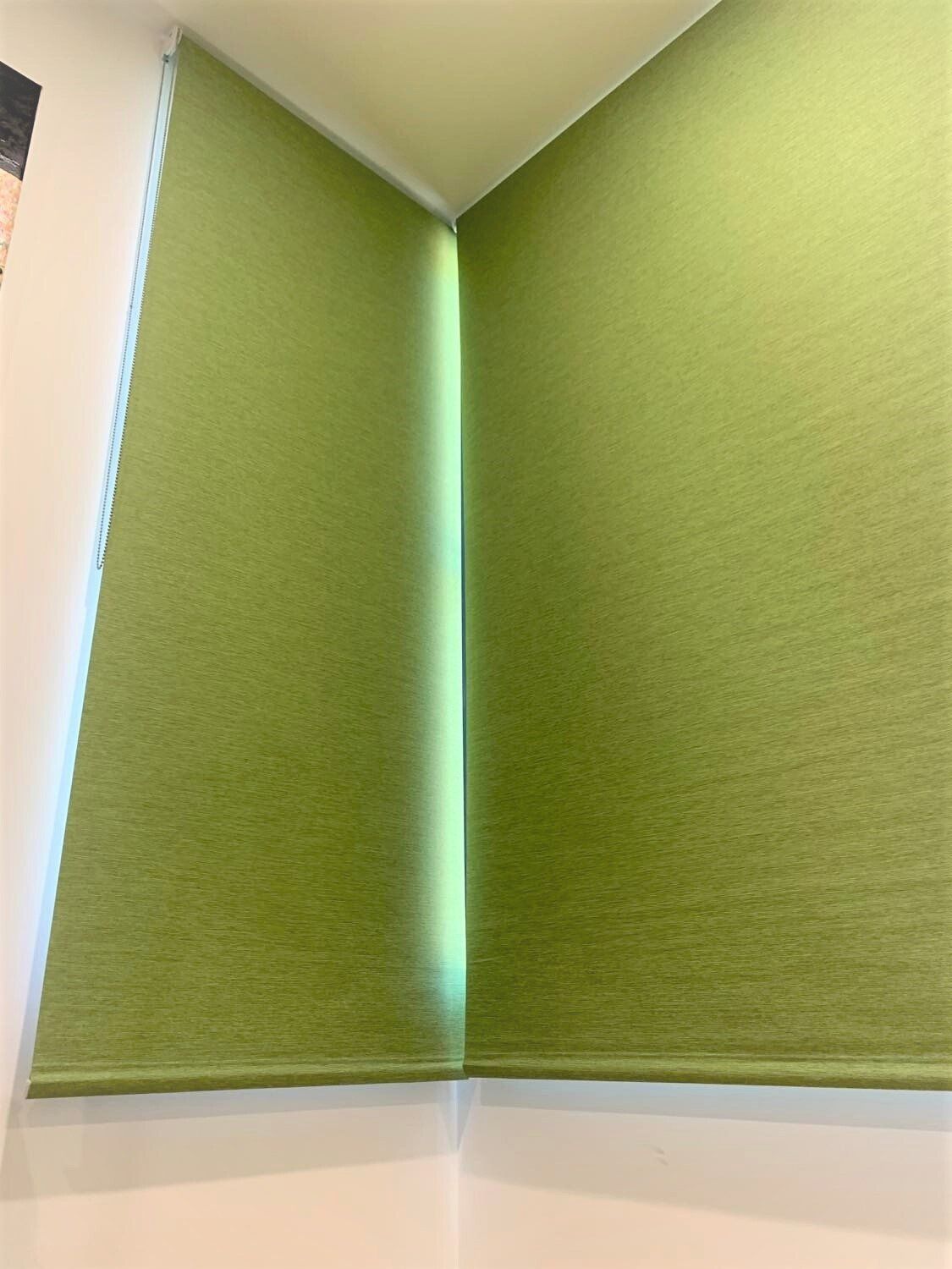 Two Green Roller Shades Meet at A Corner in A Room — Alice Mobile Blinds in Ciccone, NT