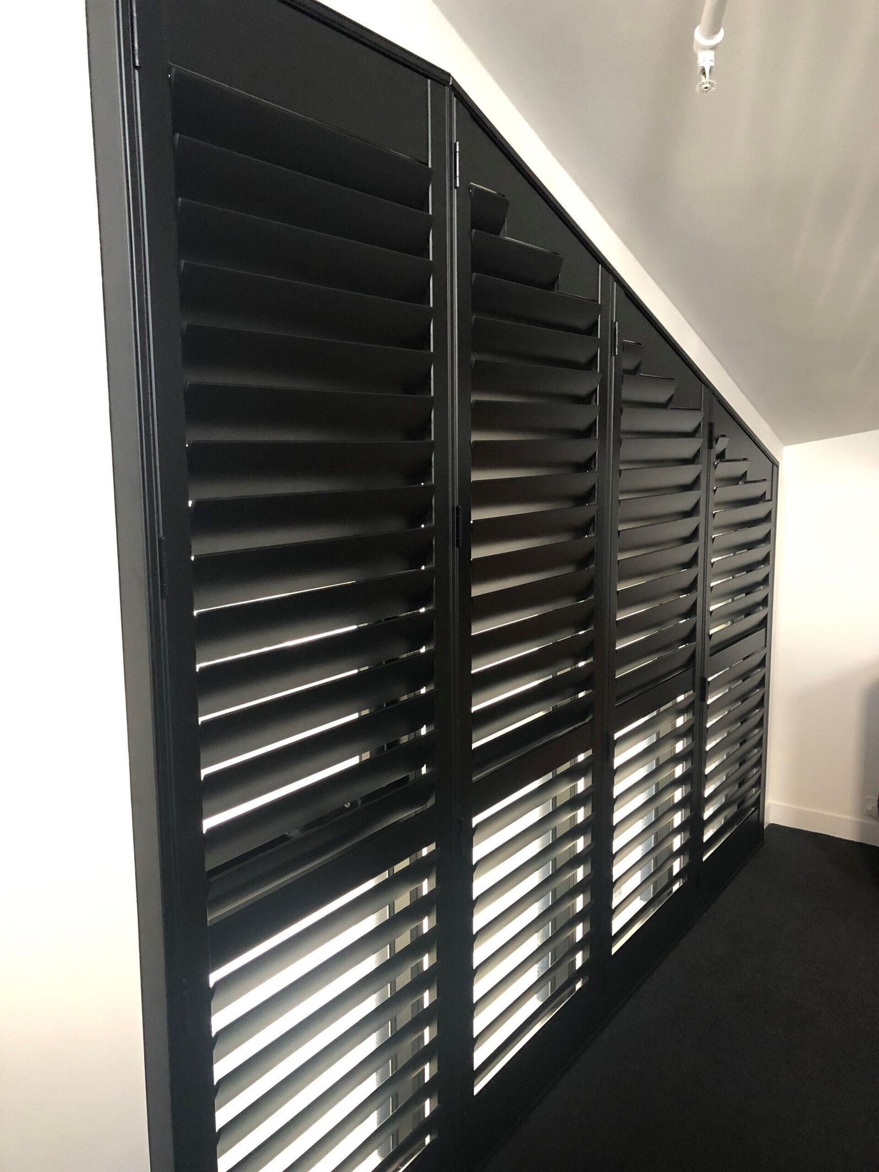 Black Louvered Shutters on An Angled Window — Alice Mobile Blinds in Ciccone, NT