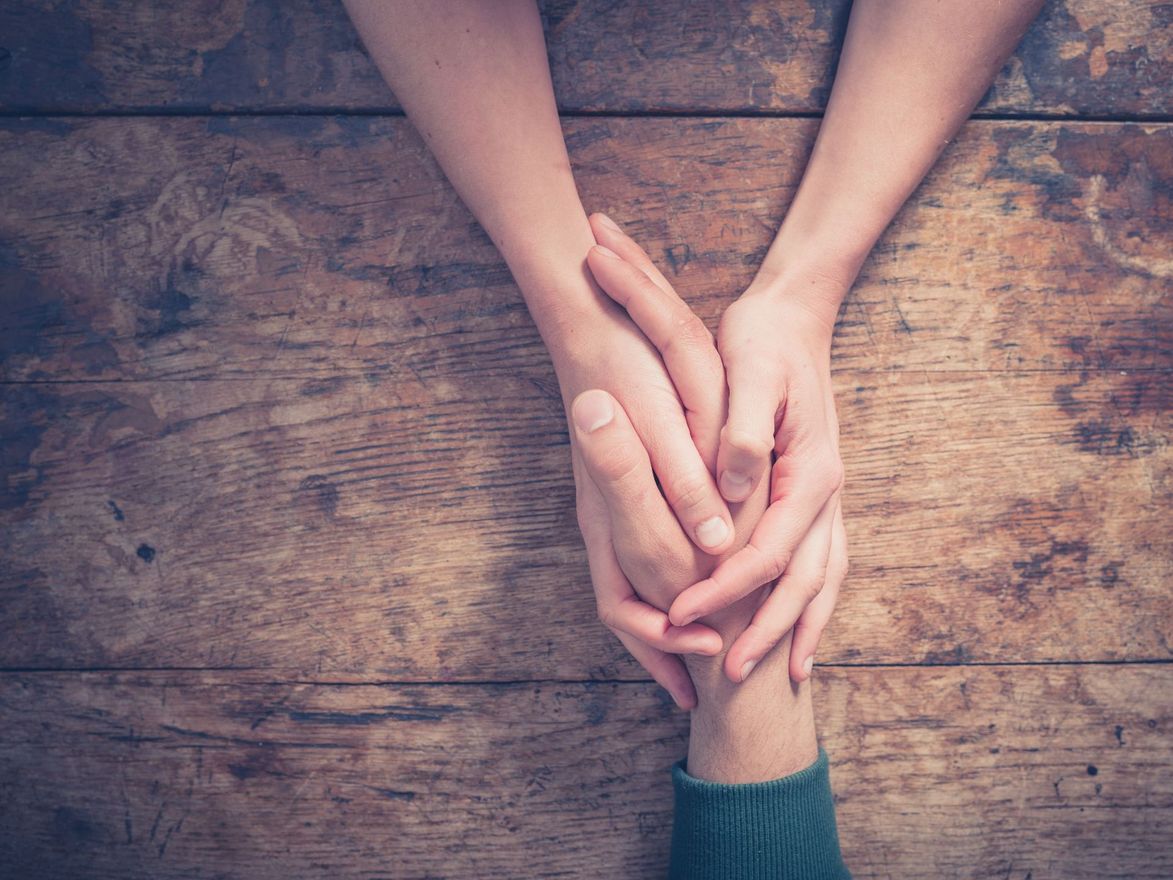 a couple holding hands on a wooden table