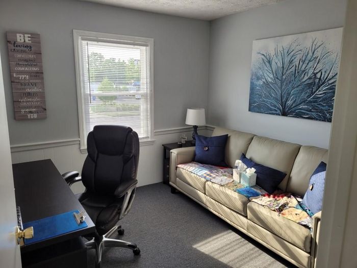 A living room with a couch , desk and chair.