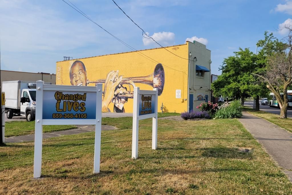a sign that says changed lives in front of a yellow building