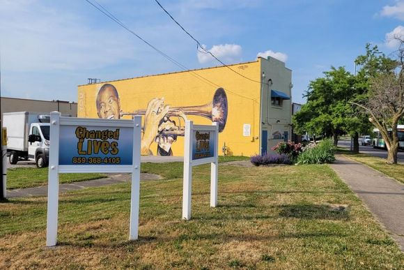 a sign that says changed lives in front of a yellow building