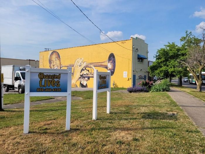 A mural of a man playing a trumpet is on the side of a building.