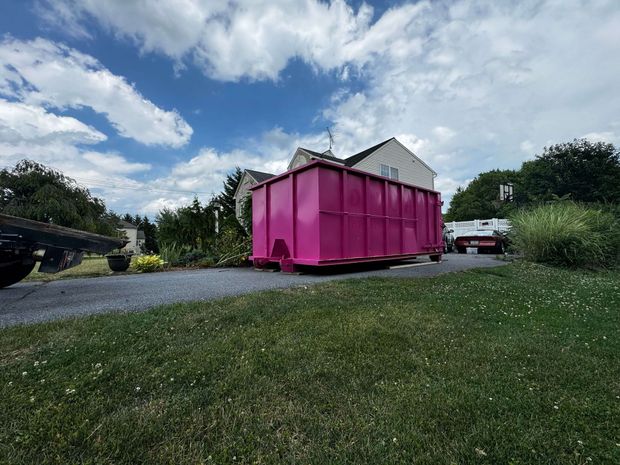 A large pink dumpster is parked in front of a house. Dumpster Rental Lancaster