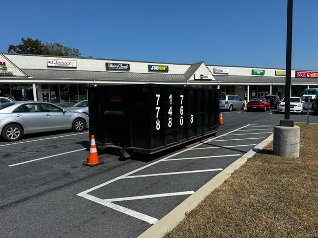A dumpster is parked in a parking lot in front of a shopping center. Dumpster Rental Lancaster, Pa