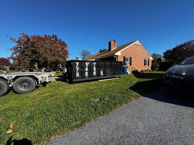 A dumpster on a trailer is parked in front of a house. Dumpster Rental Lancaster