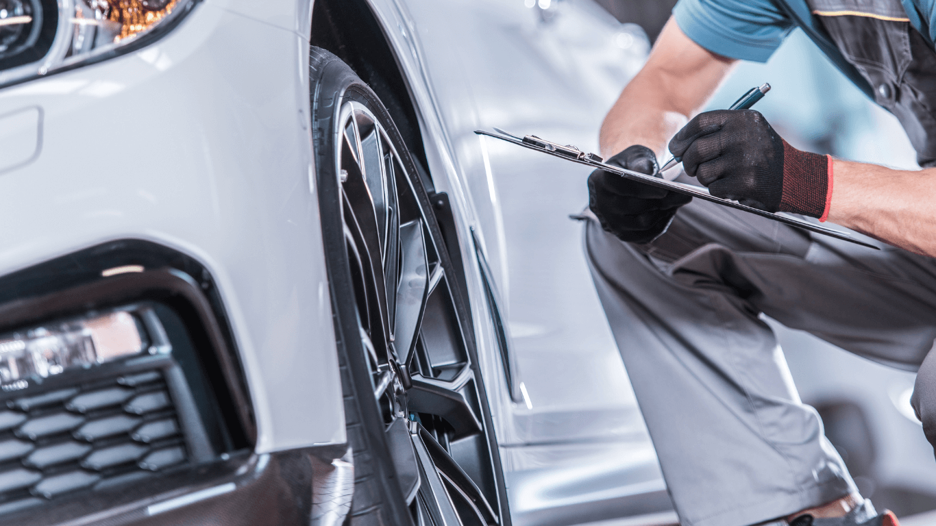 picture of a mechanic with a clipboard next to a white car