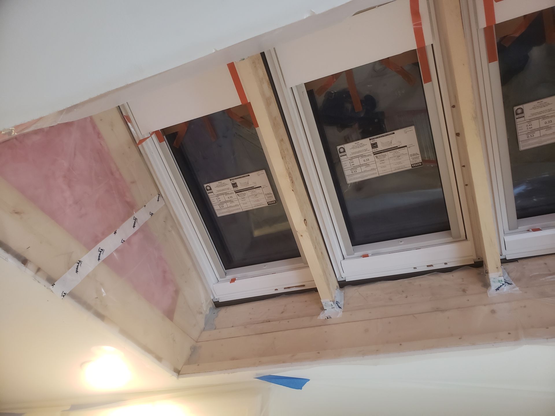 Two windows are being installed in a room under construction.