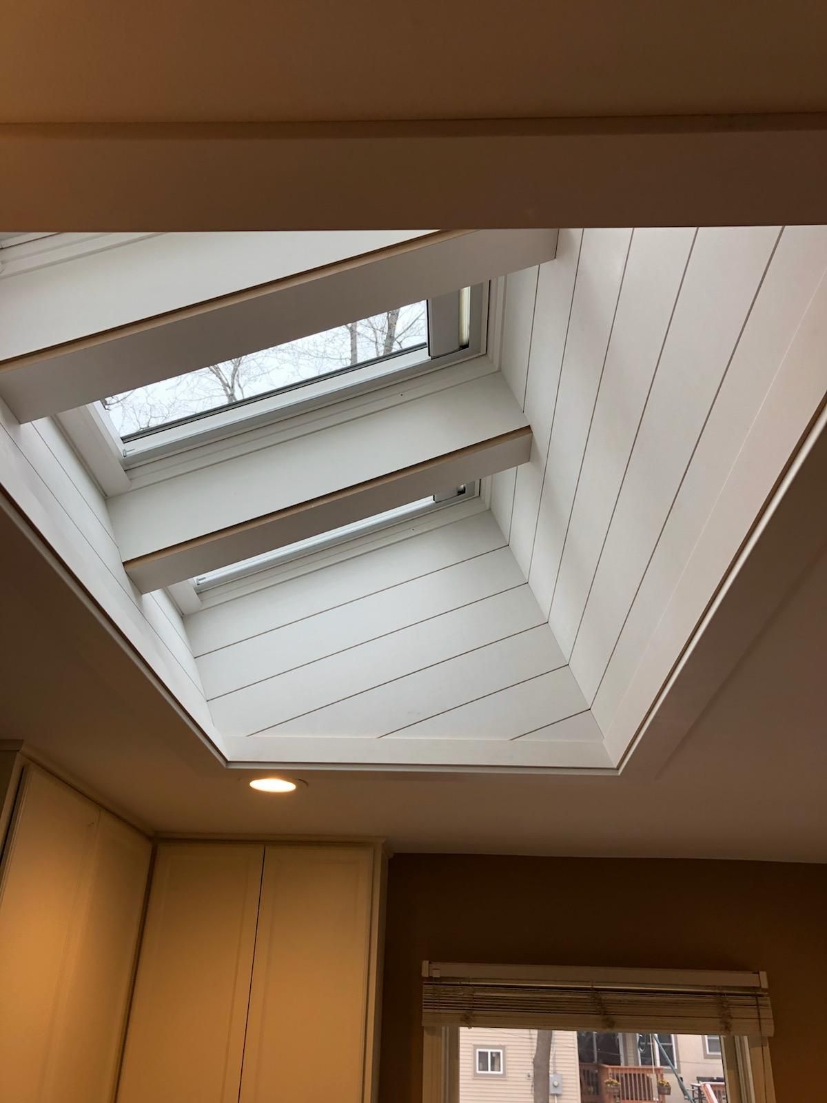 A kitchen with a skylight in the ceiling and a window.