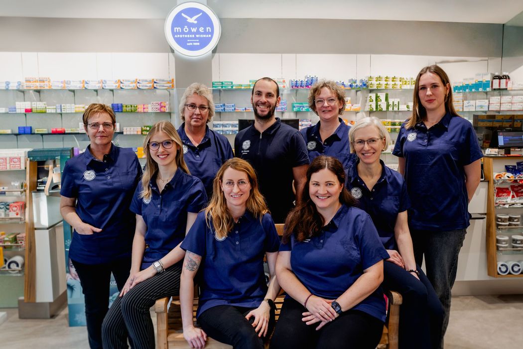 Eine Gruppe von Menschen posiert in einer Apotheke für ein Foto.