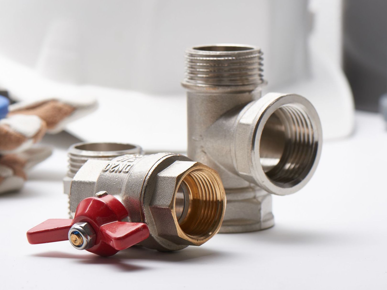 A close up of a plumbing valve with a red handle.