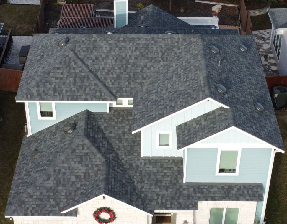 Aerial view of a house with a gray shingled roof and light blue siding.