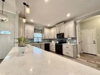 Bright modern kitchen with white cabinets, marble island, pendant lights, and stainless-steel appliances