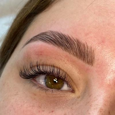 Close-up of a groomed eyebrow and eye with long lashes and warm-toned makeup