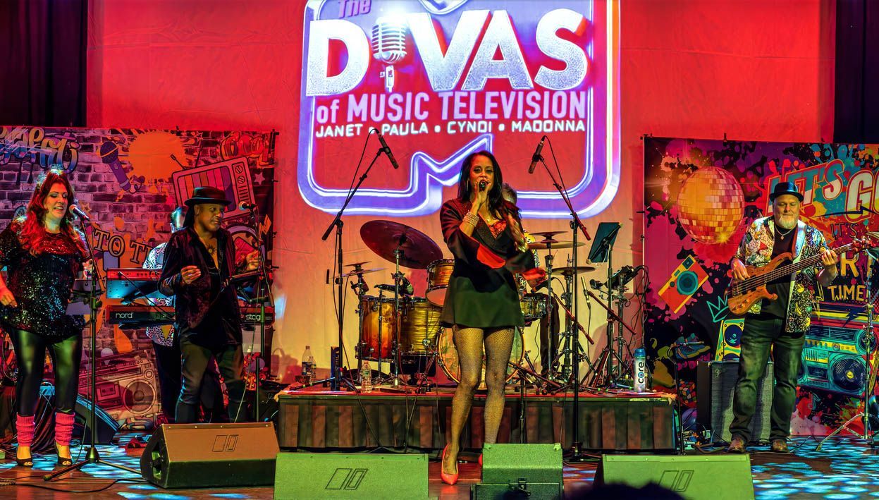 Musicians performing on a colorful stage under a “Divas of Music Television” sign.