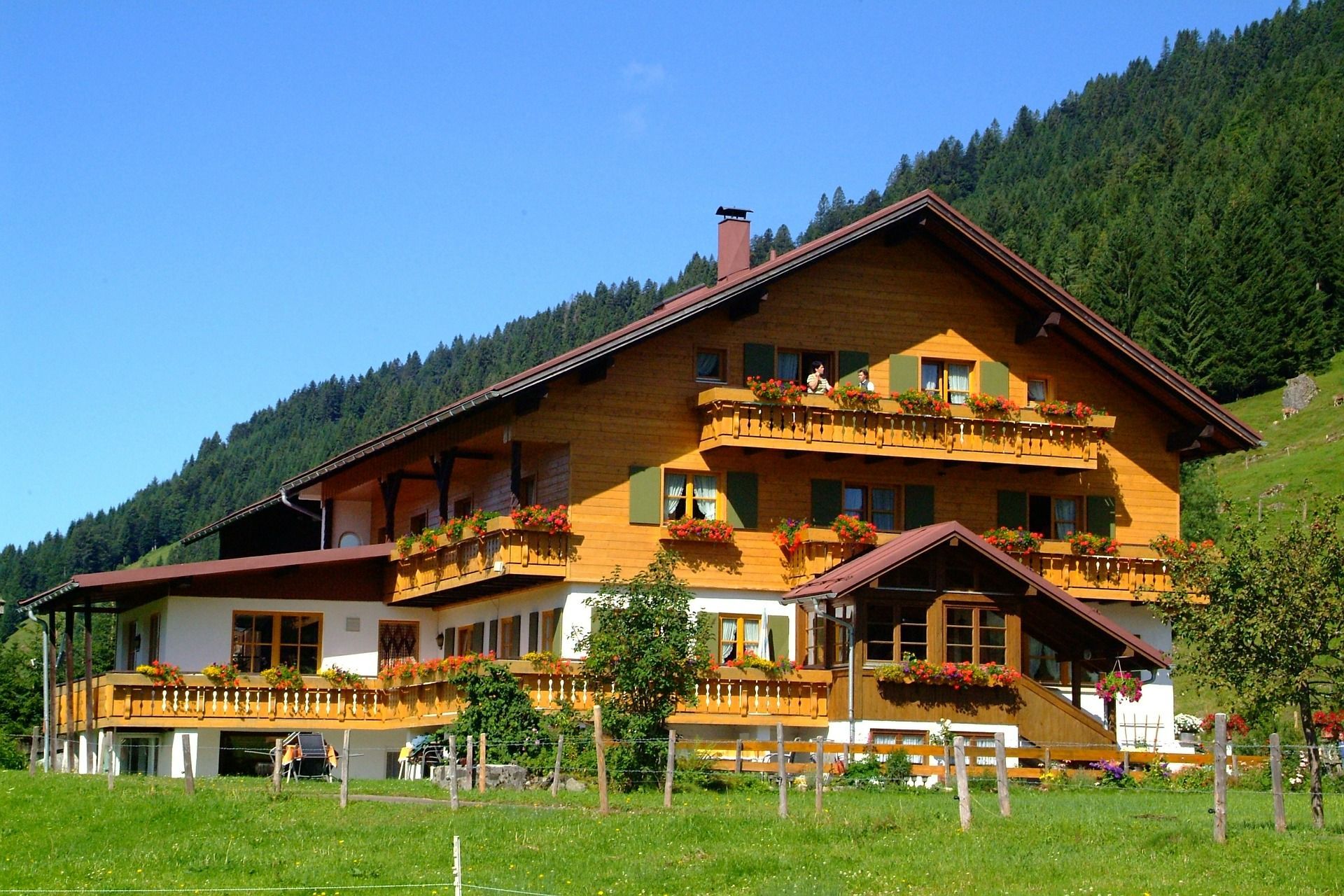 Wooden chalet with yellow balconies in a green mountain meadow under a blue sky