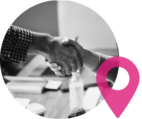 Handshake between two people in a business setting; a pink location pin is placed in the corner.