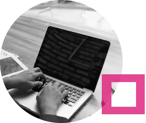 Person typing on a laptop, black and white, with a pink square.