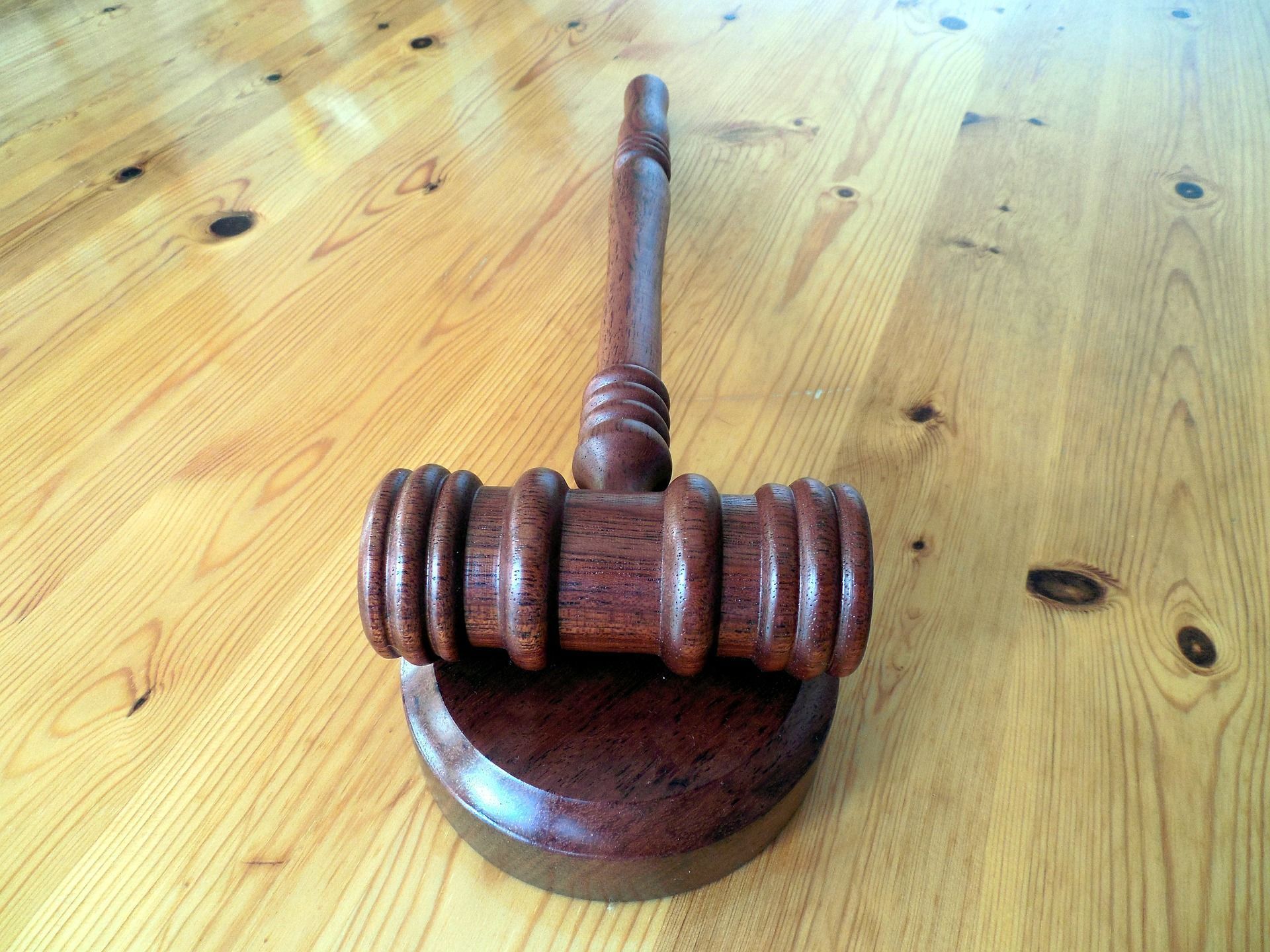 Wooden judge’s gavel on a wooden table, with a round base and ribbed head.