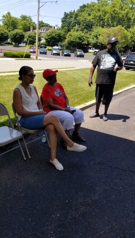 A group of people are sitting in chairs on the side of the road.