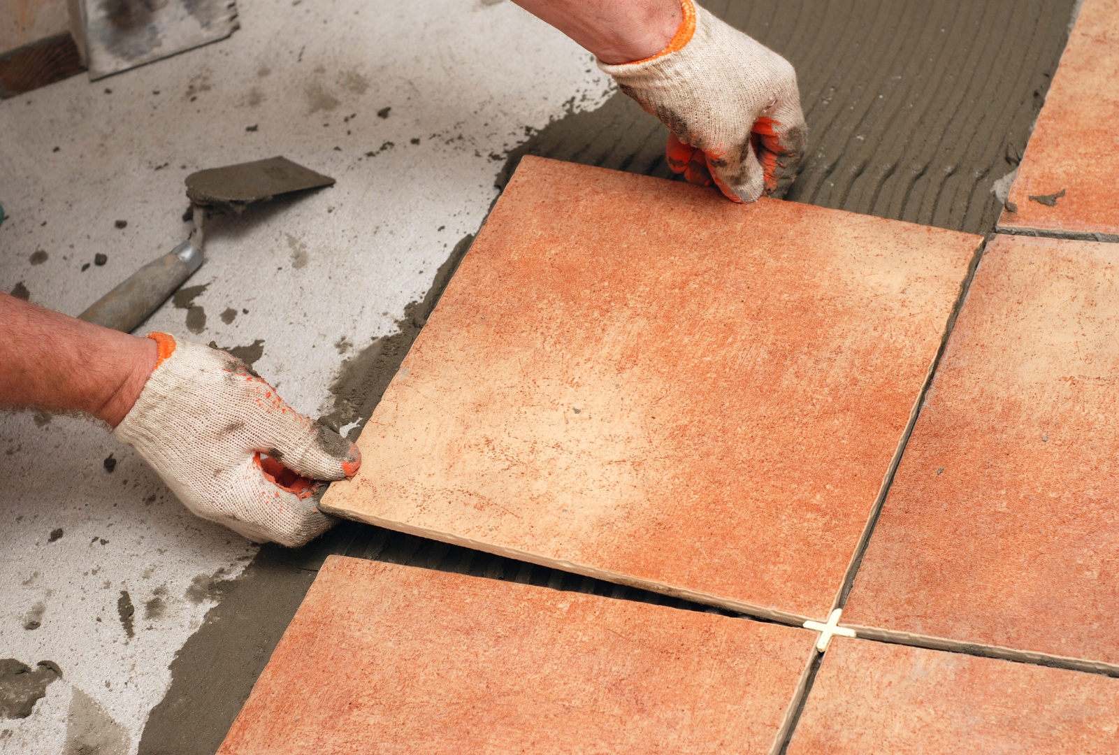 A person is laying tiles on a floor.