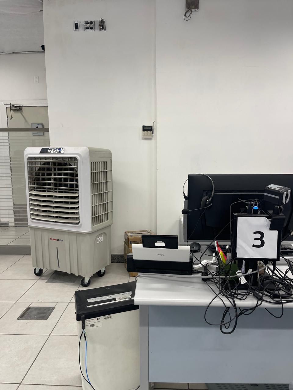 Em um escritório, um climatizador evaporativo portátil fica ao lado de uma mesa com um monitor de computador identificado com um grande número 3.