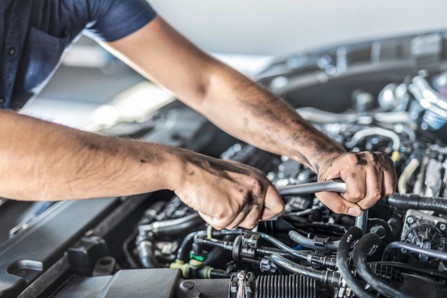 Mechanic using a wrench to work on a car engine in a garage