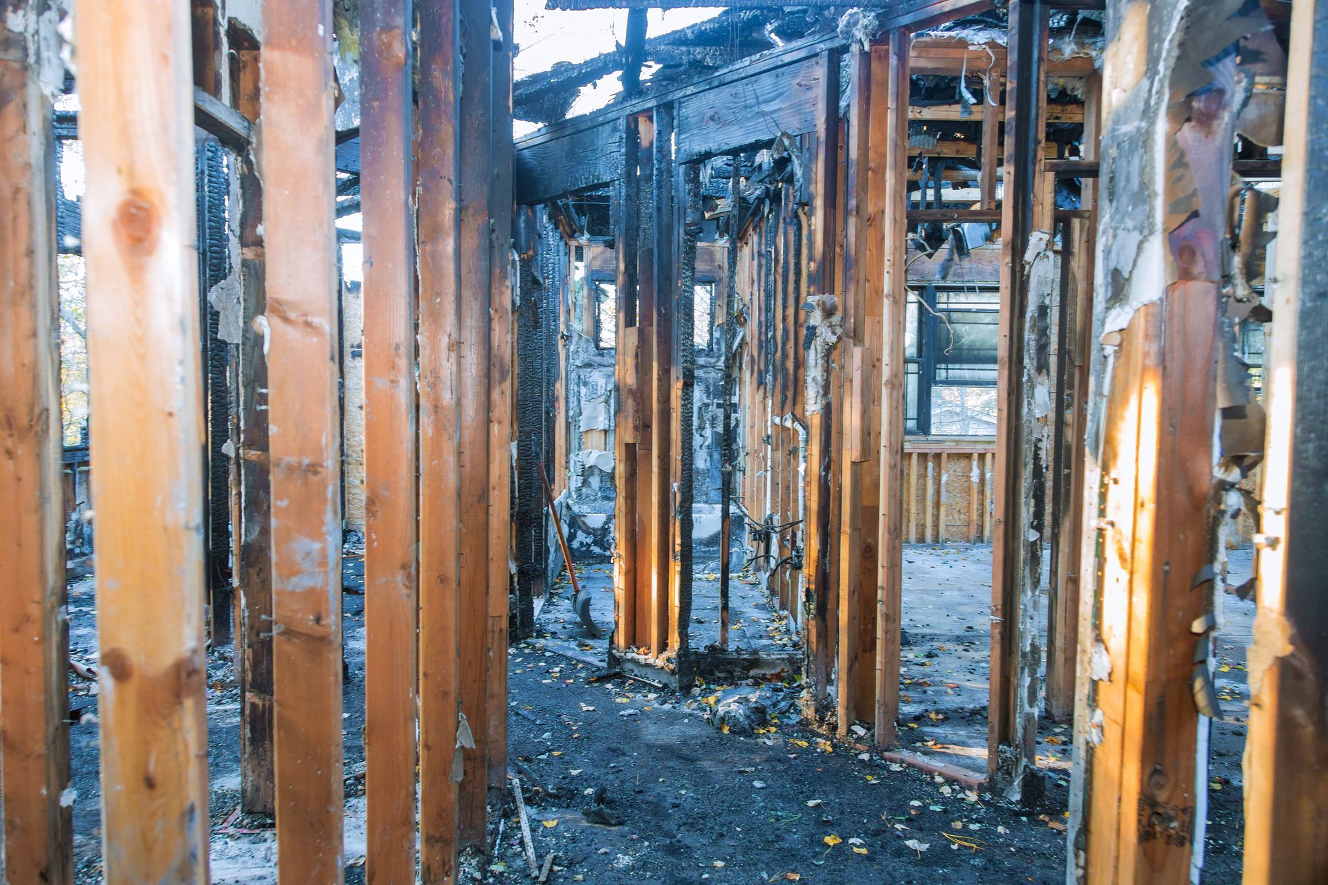 Burned-out interior of a wooden structure, charred remains visible, ash on the floor. Burned-out interior of a wooden structure, charred remains visible, ash on the floor.