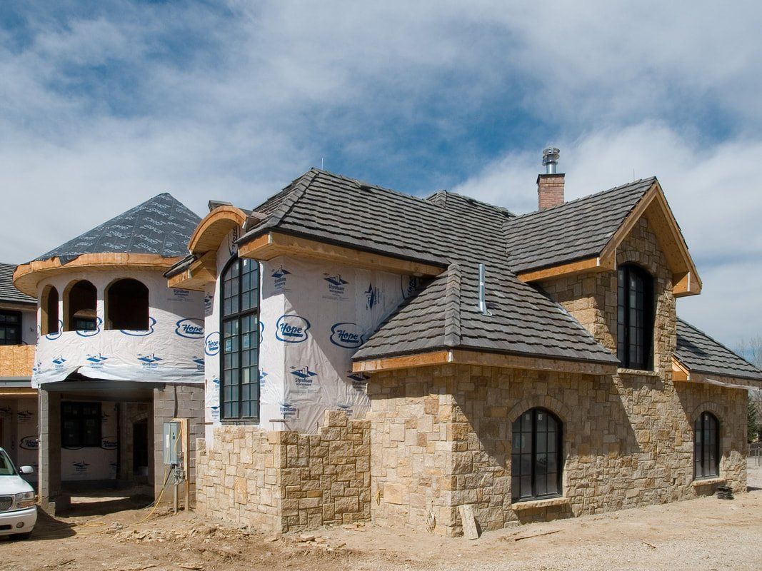 A large house is being built with a truck parked in front of it