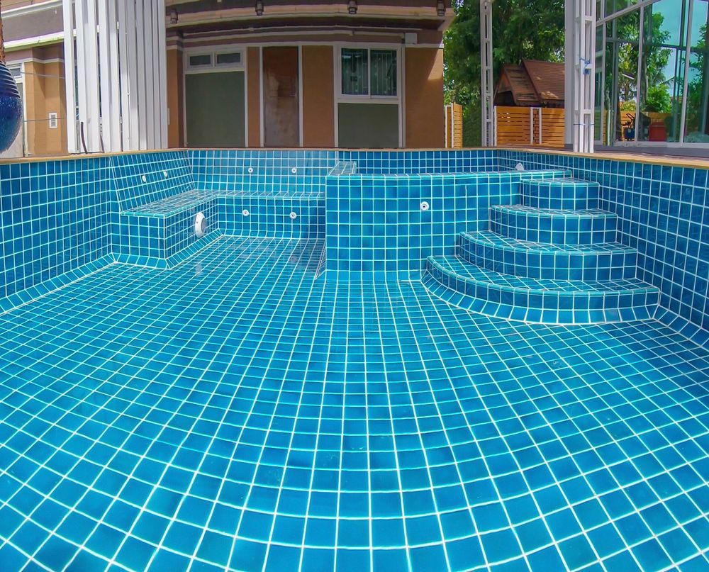 A Large Swimming Pool With Blue Tiles And Stairs — Holiday Coast Pools & Water In Woolgoolga, NSW