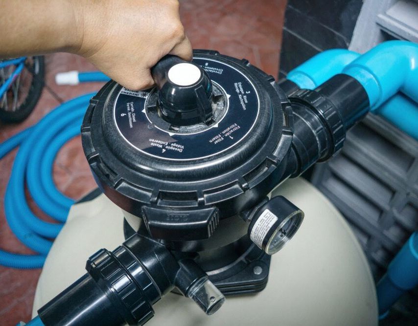 A Person Is Adjusting A Valve On A Pool Filter — Holiday Coast Pools & Water In Coffs Harbour, NSW
