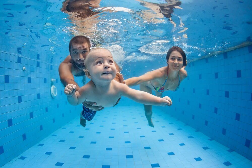 A Family Is Swimming Underwater In A Swimming Pool — Holiday Coast Pools & Water In Coffs Harbour, NSW