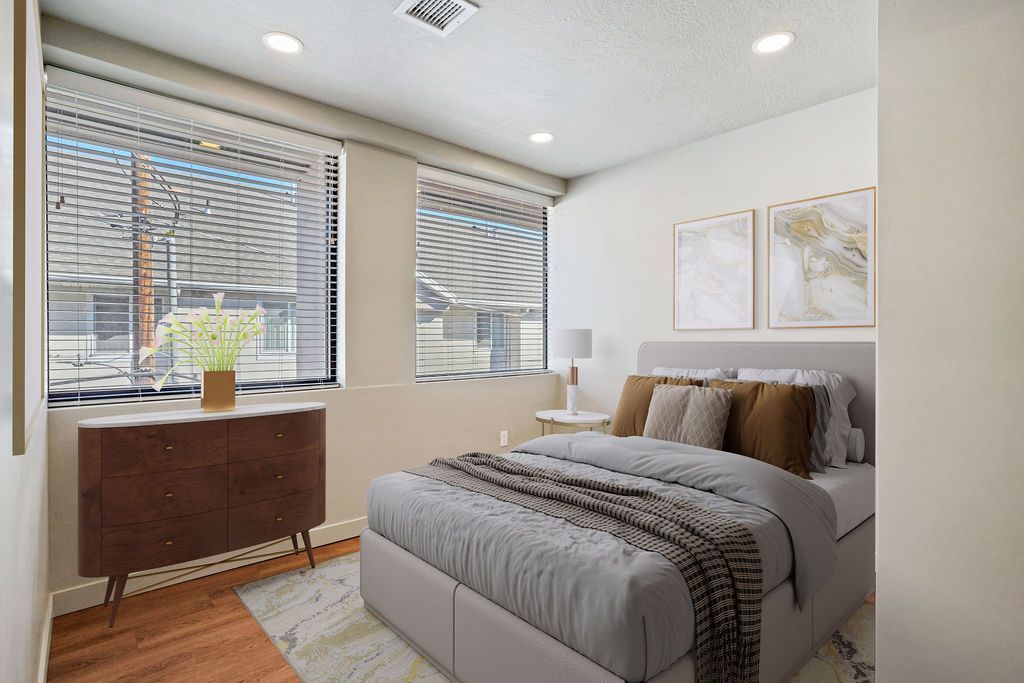 A bedroom with a bed , dresser , and two windows.
